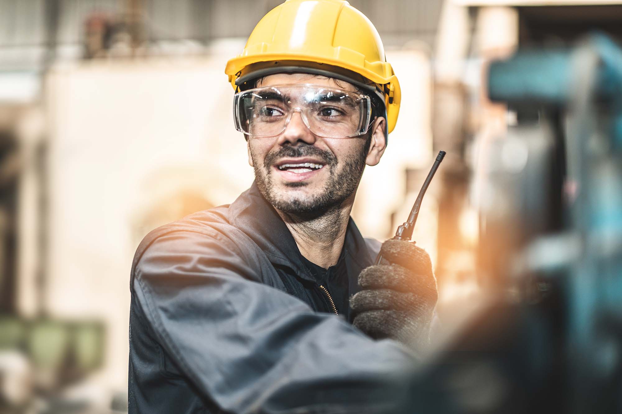 A man wearing a yellow safety helmet in an industrial facility.