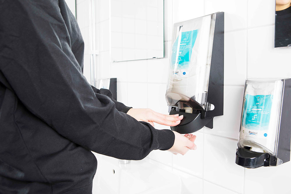 An anonymous person pumping out a dollop of soap from a Sterisol dispenser.